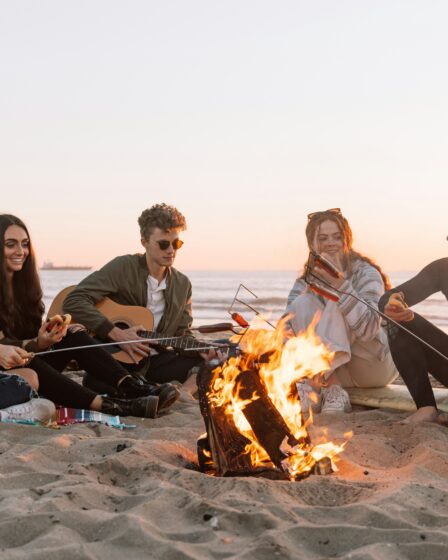 ludzie siedzący na plaży przy ognisku