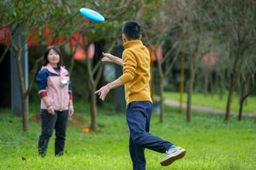 mężczyzna w parku rzucający frisbee do kobiety